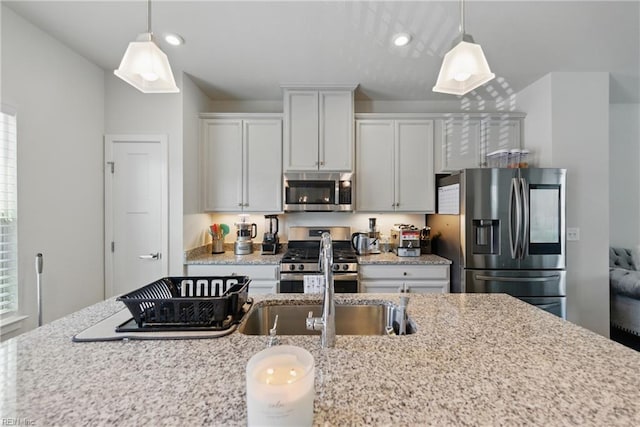 kitchen featuring stainless steel appliances, hanging light fixtures, light stone counters, recessed lighting, and white cabinets