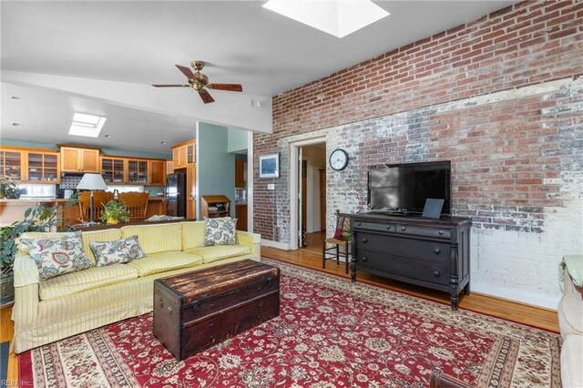 6052 Newport Cres, Norfolk, VA 23505 - living room featuring a skylight, brick wall, wood finished floors, ceiling fan, and vaulted ceiling