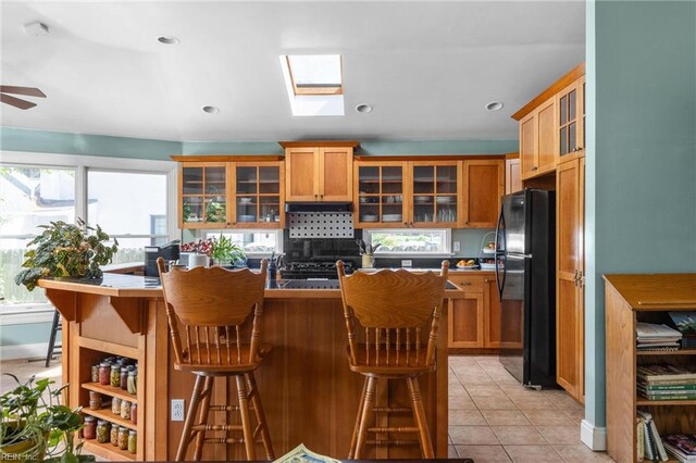 6052 Newport Cres, Norfolk, VA 23505 - kitchen featuring freestanding refrigerator, a kitchen bar, glass insert cabinets, baseboards, and a center island