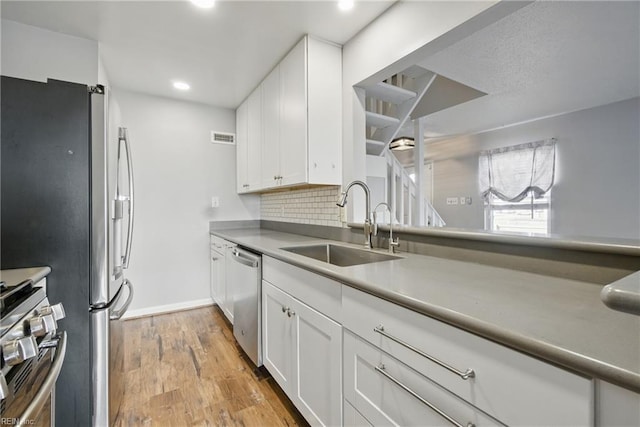 713 Quesnel Dr, Virginia Beach, VA 23454 - kitchen with a sink, stainless steel appliances, light wood-style floors, white cabinets, and tasteful backsplash