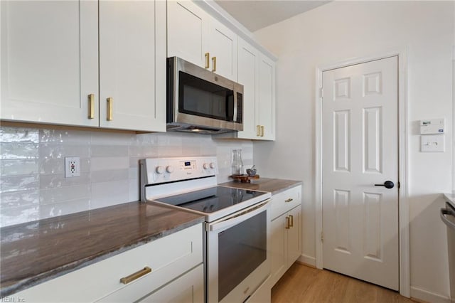3200 Jade Ct Unit 301, Virginia Beach, VA 23451 - kitchen with stainless steel microwave, electric stove, light wood finished floors, white cabinets, and decorative backsplash