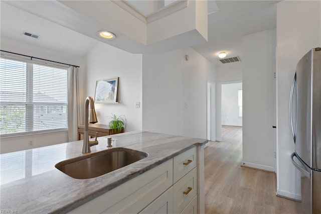 3200 Jade Ct Unit 301, Virginia Beach, VA 23451 - kitchen featuring freestanding refrigerator, a sink, white cabinets, light stone countertops, and light wood-style floors