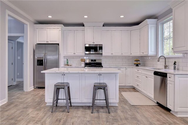 718C Poquoson Ave, Poquoson, VA 23662 - kitchen featuring appliances with stainless steel finishes, ornamental molding, white cabinets, a center island, and a kitchen bar