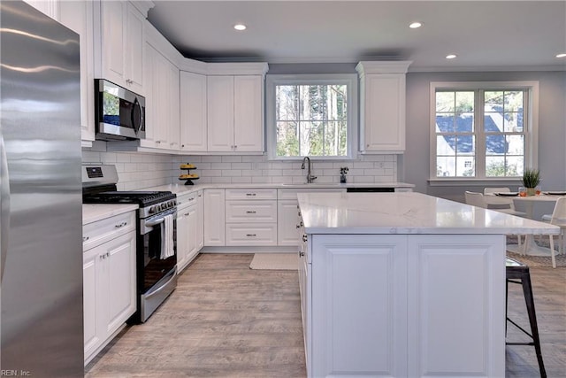 718C Poquoson Ave, Poquoson, VA 23662 - kitchen featuring appliances with stainless steel finishes, a sink, light wood-type flooring, a kitchen breakfast bar, and a center island
