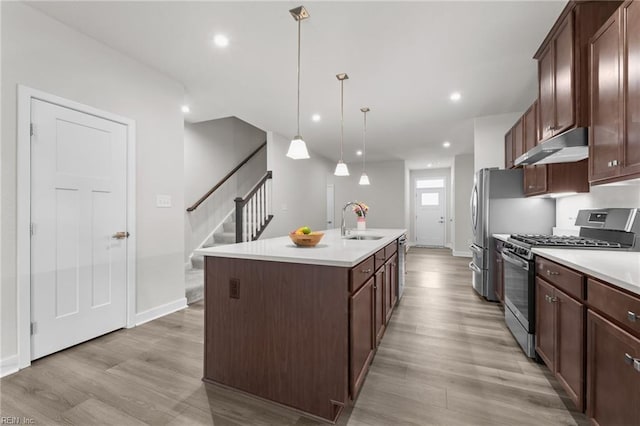 23050 Preserve Pl, Carrollton, VA 23314 - kitchen featuring stainless steel range with gas cooktop, under cabinet range hood, a sink, light wood-style floors, and a kitchen island with sink