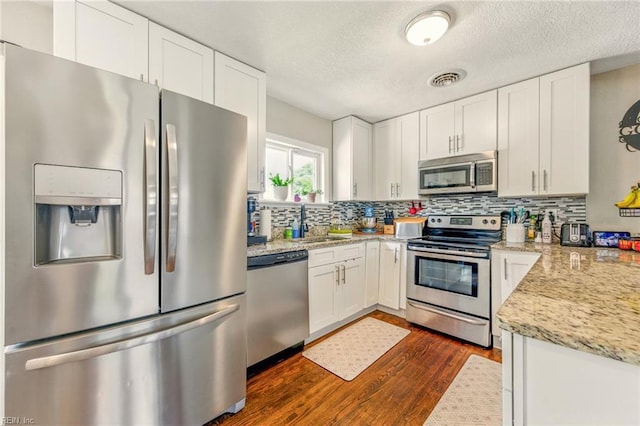 7413 Doummar Dr, Norfolk, VA 23518 - kitchen featuring appliances with stainless steel finishes, dark wood-style flooring, tasteful backsplash, a textured ceiling, and white cabinetry
