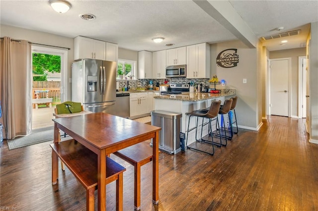 7413 Doummar Dr, Norfolk, VA 23518 - kitchen featuring appliances with stainless steel finishes, a peninsula, dark wood-type flooring, white cabinetry, and a textured ceiling