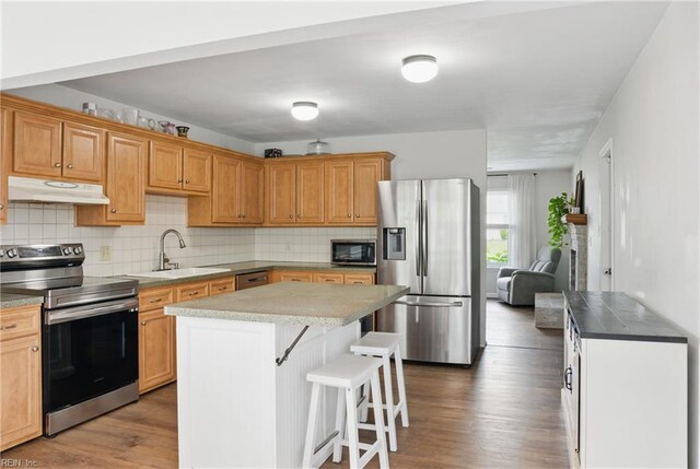 3613 Mostiler Pl, Chesapeake, VA 23323 - kitchen featuring stainless steel appliances, under cabinet range hood, a sink, a breakfast bar, and wood finished floors