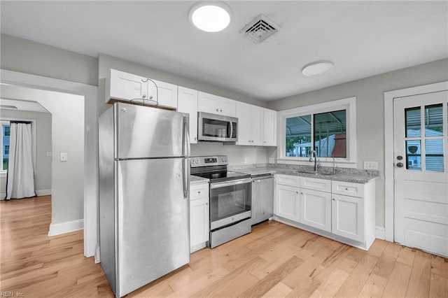 1424 Stewart St, Chesapeake, VA 23324 - kitchen with appliances with stainless steel finishes, a sink, white cabinetry, light wood-style flooring, and light stone countertops