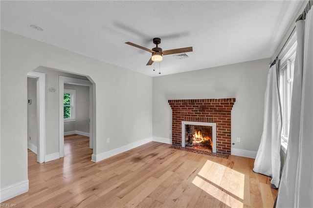 1424 Stewart St, Chesapeake, VA 23324 - unfurnished living room featuring a ceiling fan, a fireplace, arched walkways, and light wood-style flooring