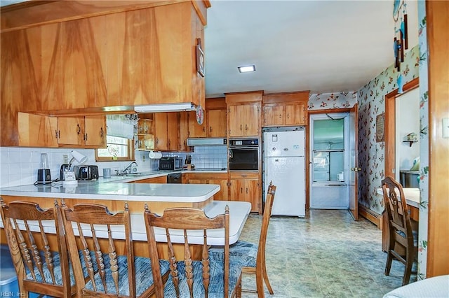 409 Briarfield Dr, Chesapeake, VA 23322 - kitchen with black appliances, brown cabinetry, a sink, light countertops, and a peninsula