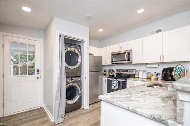 2511 Pringle Dr, Chesapeake, VA 23325 - kitchen featuring appliances with stainless steel finishes, stacked washer / dryer, light stone countertops, white cabinetry, and recessed lighting
