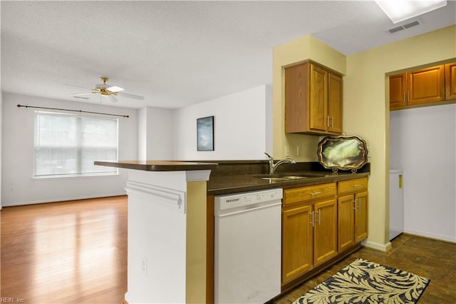 303 Settlement Dr Unit 303, Williamsburg, VA 23188 - kitchen featuring white dishwasher, dark countertops, a sink, brown cabinetry, and a peninsula