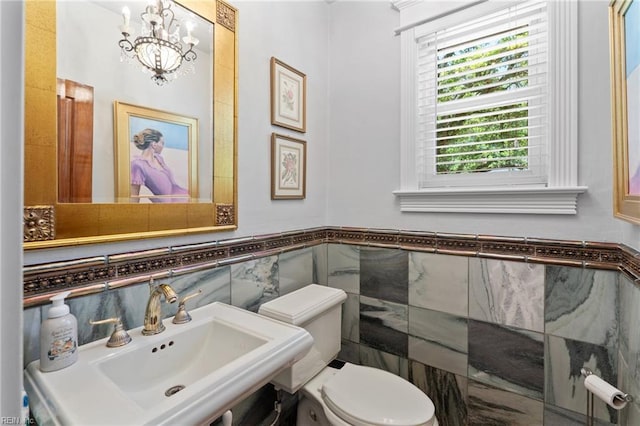 511 Brackenridge Ave, Norfolk, VA 23505 - bathroom with tile walls, a chandelier, toilet, a sink, and a wainscoted wall