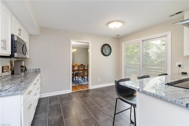 8 Assembly Ct, Newport News, VA 23606 - kitchen with stainless steel microwave, white cabinetry, light stone countertops, and baseboards
