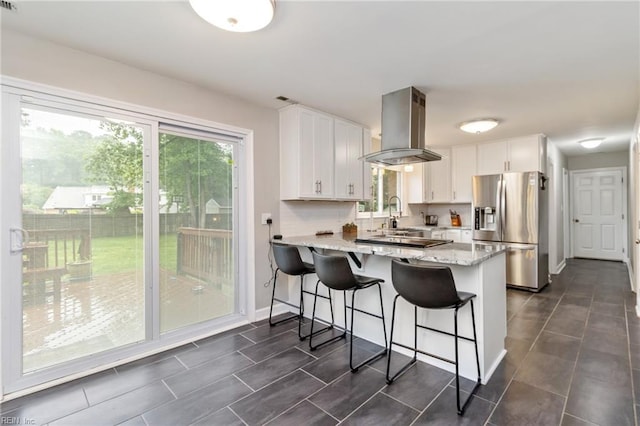 8 Assembly Ct, Newport News, VA 23606 - kitchen with stainless steel fridge, island range hood, white cabinets, a peninsula, and light stone counters