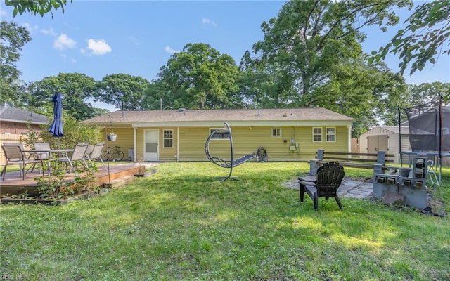 4917 Erskine St, Virginia Beach, VA 23462 - back of property featuring a trampoline, a wooden deck, a yard, outdoor dining space, and a fire pit