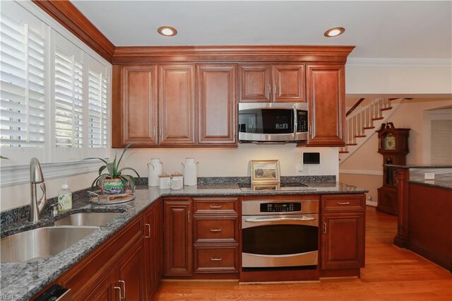 609 River Rd, Newport News, VA 23601 - kitchen with appliances with stainless steel finishes, a sink, dark stone counters, ornamental molding, and light wood-style floors