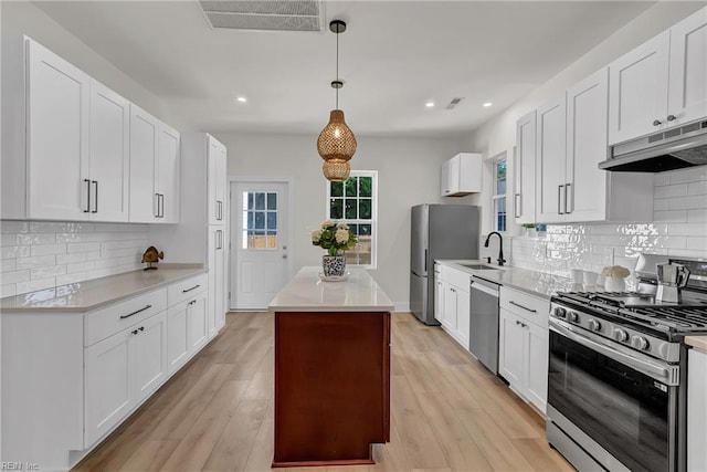 1028 W 36th St, Norfolk, VA 23508 - kitchen with stainless steel appliances, under cabinet range hood, a center island, light countertops, and white cabinetry