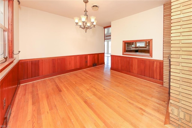 101 Elmhurst Ln, Portsmouth, VA 23701 - unfurnished dining area with light wood-style flooring, a chandelier, wainscoting, and wooden walls
