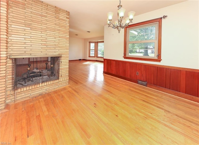 101 Elmhurst Ln, Portsmouth, VA 23701 - unfurnished living room with wood finished floors, wainscoting, a chandelier, a fireplace, and wood walls