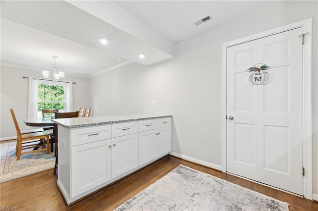 101 Huxley Pl, Newport News, VA 23606 - kitchen with a peninsula, a chandelier, white cabinets, dark wood-style flooring, and crown molding