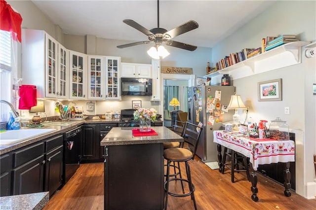 218 Mt Vernon Ave, Portsmouth, VA 23707 - kitchen with black appliances, a sink, dark cabinets, a kitchen island, and wood finished floors