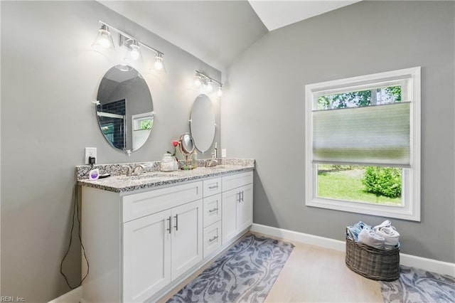 611 74th St, Newport News, VA 23605 - bathroom featuring double vanity, plenty of natural light, lofted ceiling, wood finished floors, and baseboards