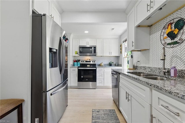 611 74th St, Newport News, VA 23605 - kitchen featuring appliances with stainless steel finishes, a sink, decorative backsplash, light wood-style flooring, and white cabinetry