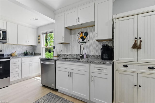 611 74th St, Newport News, VA 23605 - kitchen with appliances with stainless steel finishes, a sink, decorative backsplash, light wood finished floors, and white cabinetry