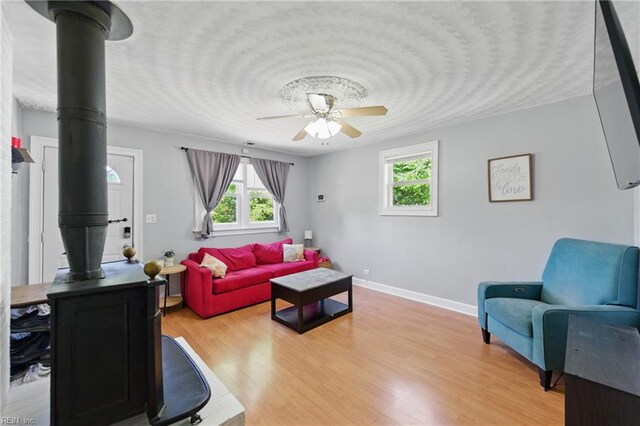 1219 Milton St, Norfolk, VA 23505 - living room with a wood stove, ceiling fan, healthy amount of natural light, light wood-style flooring, and a textured ceiling