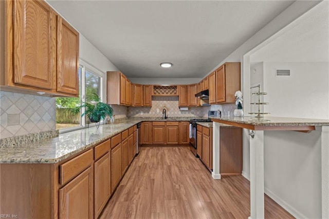 3521 Melinda Pl, Virginia Beach, VA 23452 - kitchen featuring stainless steel gas stove, under cabinet range hood, light wood-style floors, backsplash, and light stone counters