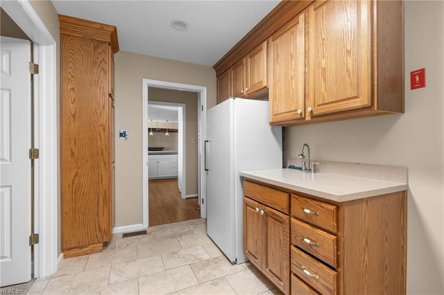1217 Cogliandro Dr, Chesapeake, VA 23320 - kitchen featuring freestanding refrigerator, light countertops, a sink, brown cabinetry, and baseboards