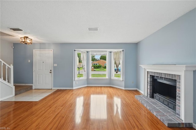 1405 Collingswood Trl, Virginia Beach, VA 23464 - unfurnished living room featuring wood finished floors, a brick fireplace, stairs, baseboards, and a textured ceiling