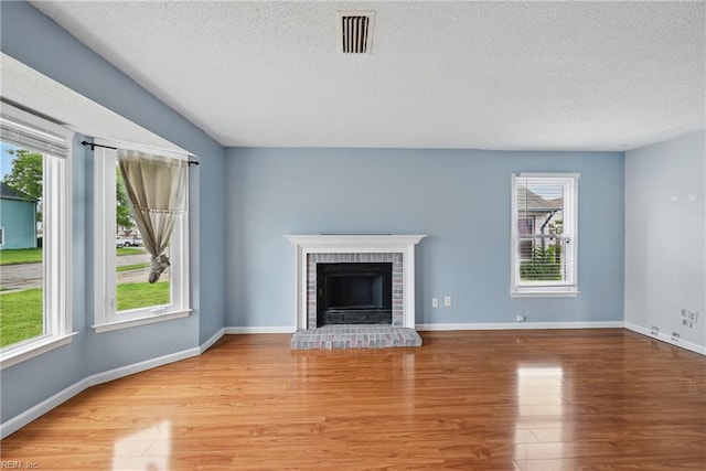 1405 Collingswood Trl, Virginia Beach, VA 23464 - unfurnished living room featuring light wood finished floors, a textured ceiling, a brick fireplace, and baseboards
