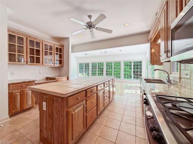 133 Sugar Bush, Williamsburg, VA 23188 - kitchen with stainless steel appliances, a sink, light tile patterned floors, glass insert cabinets, and brown cabinetry