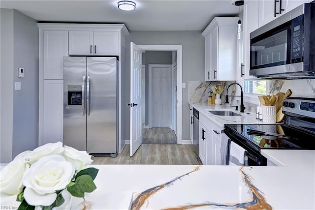 717 S Fallon Ct, Hampton, VA 23661 - kitchen with stainless steel appliances, a sink, white cabinets, light wood-type flooring, and tasteful backsplash