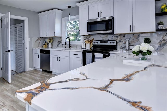 717 S Fallon Ct, Hampton, VA 23661 - kitchen with stainless steel appliances, a sink, white cabinets, light wood-style floors, and decorative backsplash