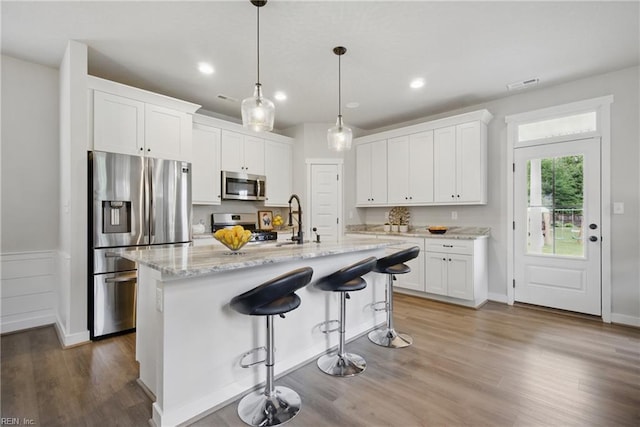 653 Waters Rd, Chesapeake, VA 23322 - kitchen featuring stainless steel appliances, white cabinets, wood finished floors, a sink, and light stone counters