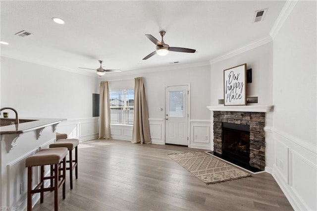23 Mallory Way, Hampton, VA 23664 - living room featuring a decorative wall, a ceiling fan, a stone fireplace, wainscoting, and crown molding
