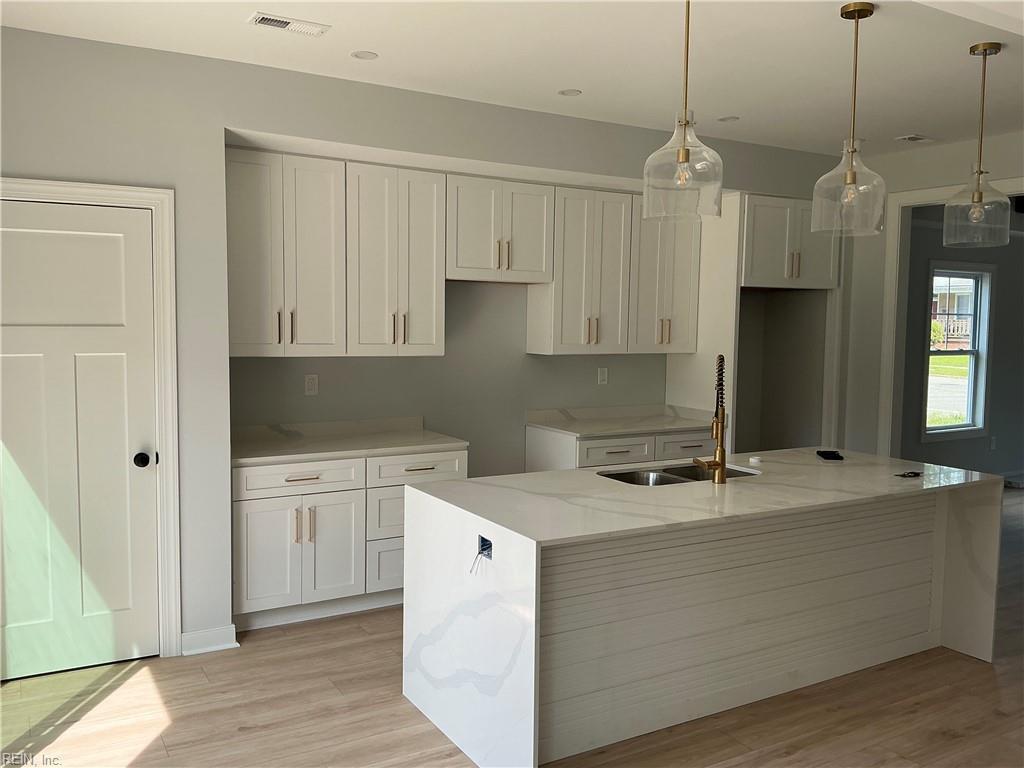 341 Blair Ave, Newport News, VA 23607 - kitchen with a sink, a spacious island, light wood-style floors, light stone countertops, and white cabinets