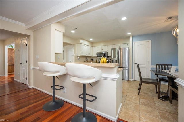 1020 Baydon Ln, Chesapeake, VA 23322 - kitchen with appliances with stainless steel finishes, a peninsula, crown molding, a breakfast bar, and light countertops