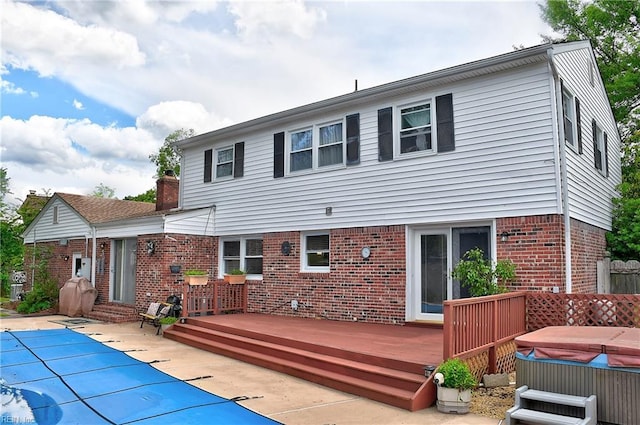 1052 Sunnyside Dr, Virginia Beach, VA 23464 - back of property with a hot tub, a wooden deck, brick siding, a patio, and a chimney
