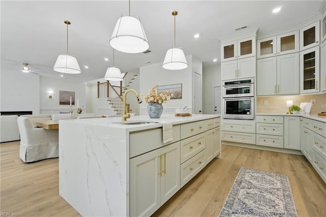 1653 Shipyard Rd, Chesapeake, VA 23323 - kitchen with stainless steel double oven, a sink, light wood finished floors, a kitchen island with sink, and pendant lighting