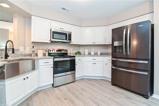6100 Amberly Cir, Suffolk, VA 23435 - kitchen featuring appliances with stainless steel finishes, light wood-style floors, a sink, white cabinetry, and light stone countertops
