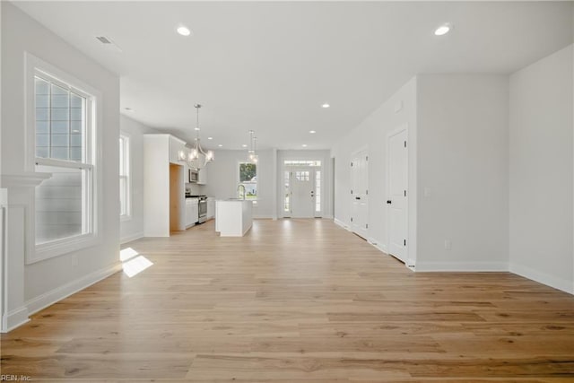 225 Ayrshire Loop, Smithfield, VA 23430 - unfurnished living room with a chandelier, light wood-style flooring, baseboards, recessed lighting, and a sink