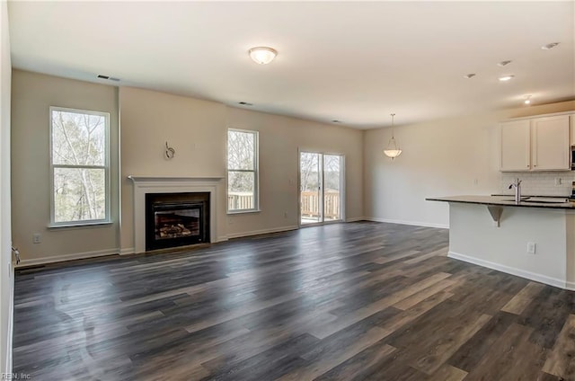 108 Brassy St, Suffolk, VA 23434 - unfurnished living room featuring dark wood-type flooring, a glass covered fireplace, baseboards, and recessed lighting