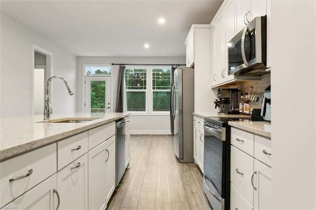 1544 Stanford Ln, Newport News, VA 23608 - kitchen with appliances with stainless steel finishes, a sink, white cabinets, light wood finished floors, and light stone countertops