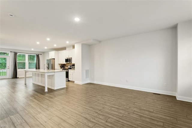 1544 Stanford Ln, Newport News, VA 23608 - kitchen with appliances with stainless steel finishes, white cabinets, a kitchen bar, a kitchen island, and wood finished floors