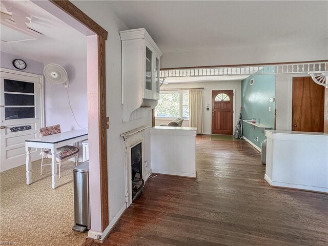 1625 Garfield Dr, Norfolk, VA 23503 - kitchen with dark wood finished floors, white cabinets, glass insert cabinets, baseboards, and a glass covered fireplace